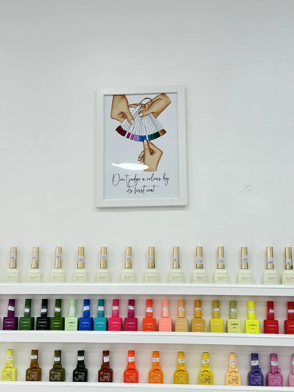 The polish shelf: rows of coloured bottles under a nail art print